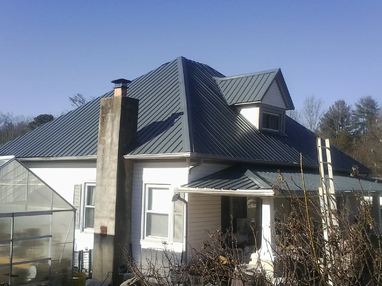 Dark blue standing seam metal roof on a white farmhouse with dormer — Slate & Tile Roof Repair by Roofing Brothers in Guild