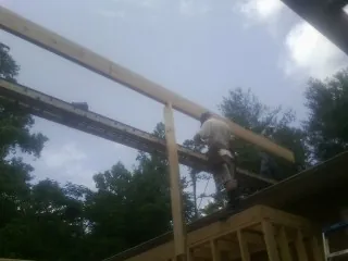 Carpenter setting a ridge beam over a new addition frame — Ice Dam Removal by Roofing Brothers in Guild
