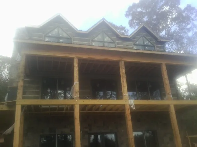 Dormers and porch framing on a large log home under construction — Roof Coating work by our crew in Guild